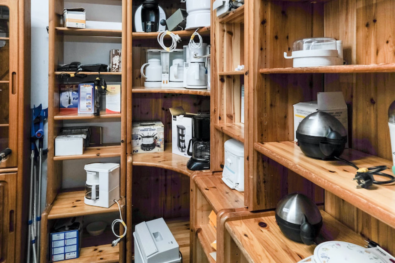 Holzregal mit verschiedenen Haushaltsger&auml;ten wie Kaffeemaschine und Wasserkocher.