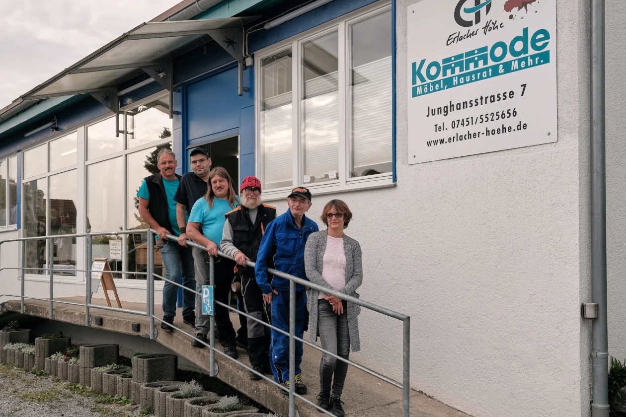 Sechs Personen stehen auf der Rampe vor dem Geb&auml;ude der Kommode Horb der Erlacher H&ouml;he. Hinter ihnen befinden sich gro&szlig;e Fenster und eine auff&auml;llige blaue Eingangst&uuml;r.