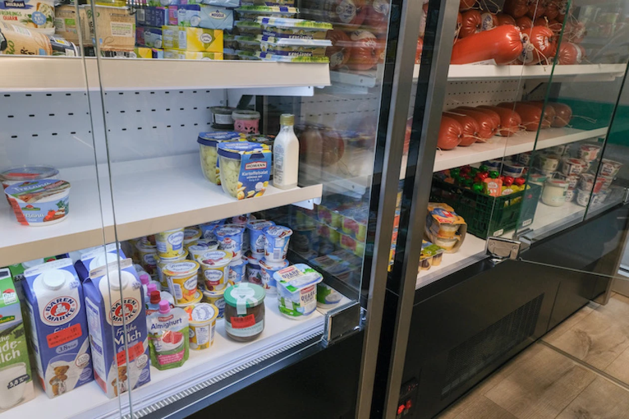 Eine K&uuml;hltheke ist gef&uuml;llt mit verschiedenen Milchprodukten wie Joghurt, Milch, Quark und Butter. Direkt daneben steht ein weiteres K&uuml;hlregal, das vorrangig mit Wurstwaren best&uuml;ckt ist.
