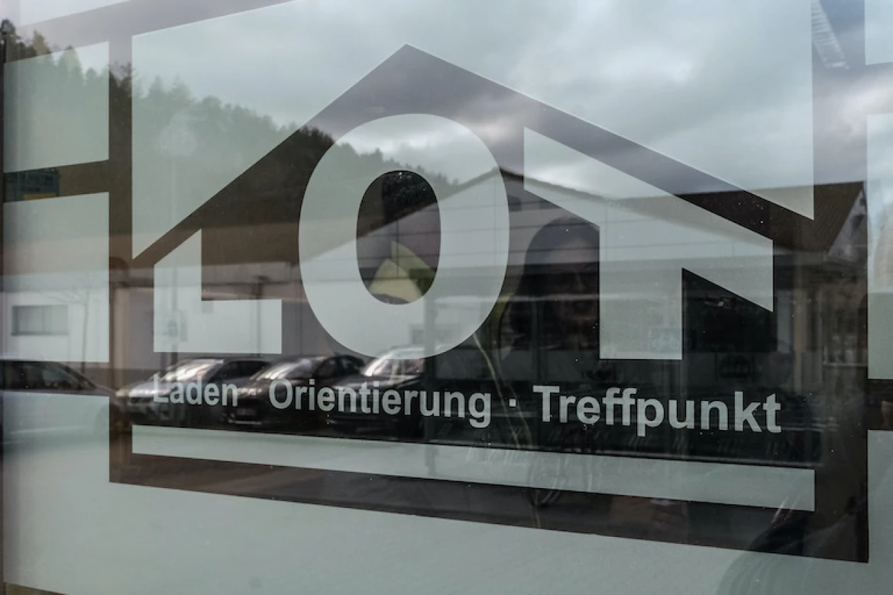 Glasscheibe mit dem Logo und Schriftzug "LOT Laden - Orientierung - Treffpunkt" der Erlacher H&ouml;he.